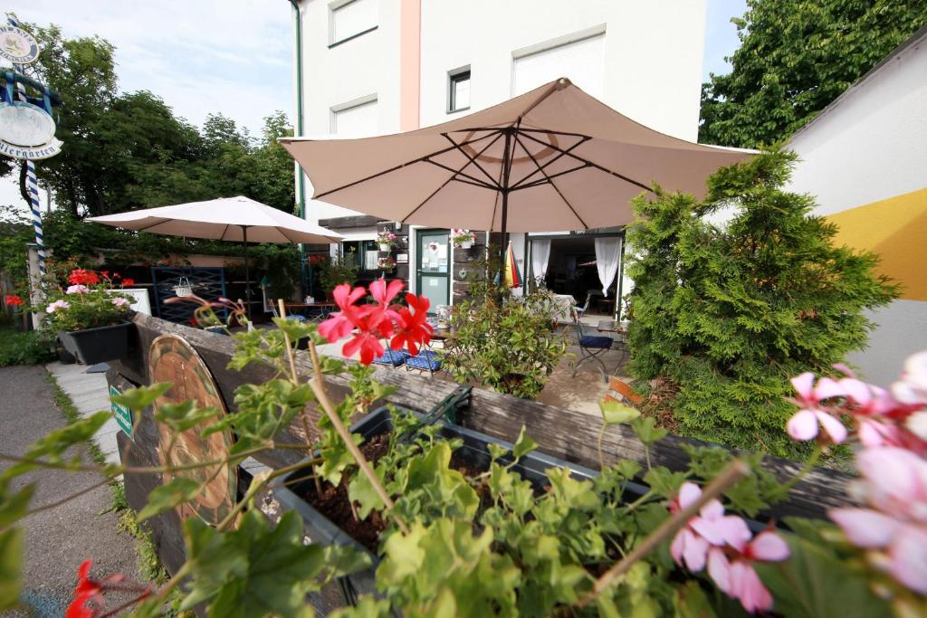 a patio with an umbrella and some flowers at LANDHAUS KLAMBAUER Ferienapartments Thermennähe St Martins Therme in Frauenkirchen