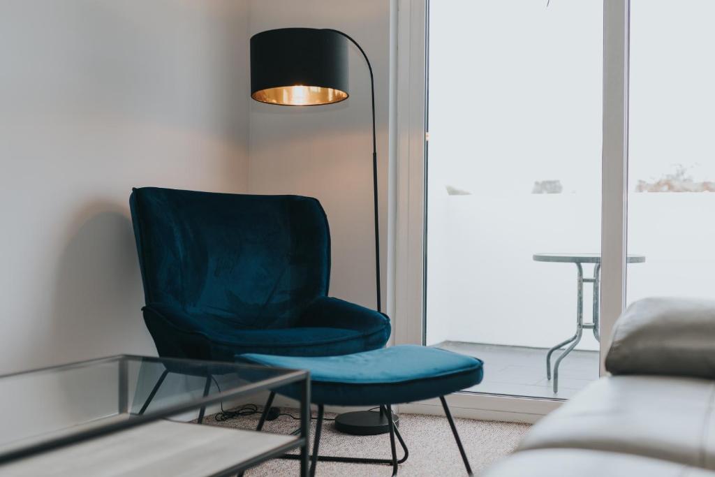 ein blauer Stuhl in einem Wohnzimmer mit einer Lampe in der Unterkunft Causeway Coast Sea Shore Apartment - Ballycastle in Ballycastle