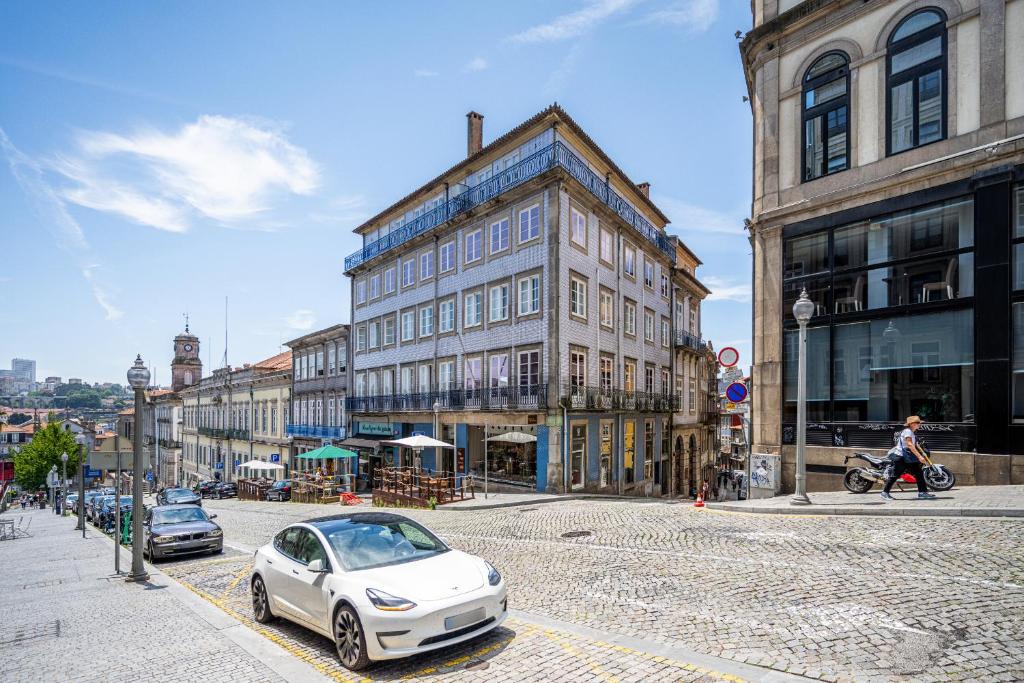 une voiture blanche garée dans une rue de la ville avec des bâtiments dans l'établissement Casas do Porto - Ribeira Apartments, à Porto