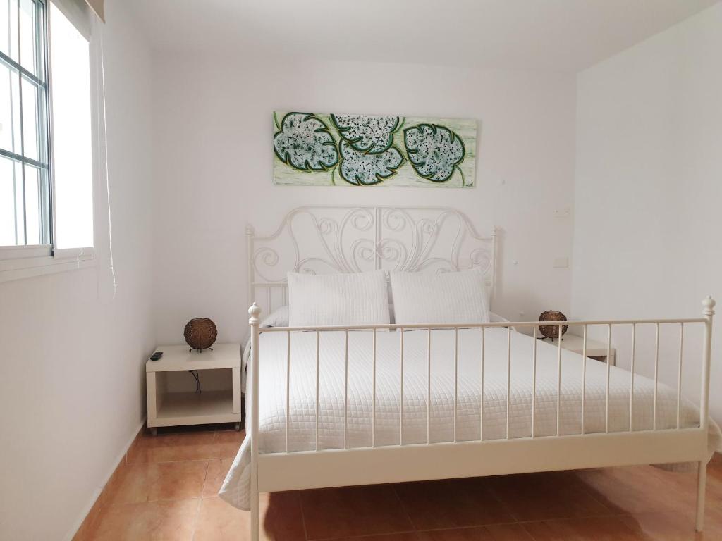 um quarto branco com uma cama branca e uma fotografia na parede em El Caramelito 3 em San Bartolomé