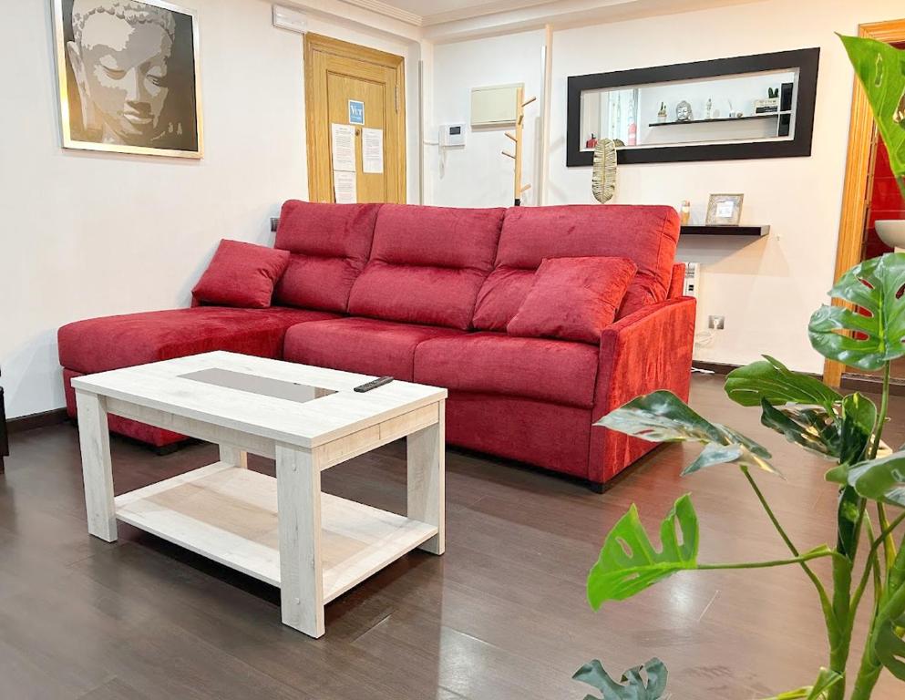 sala de estar con sofá rojo y mesa en NUEVO: 8 minutos ayuntamiento, 10 catedral, WIFI, en Oviedo