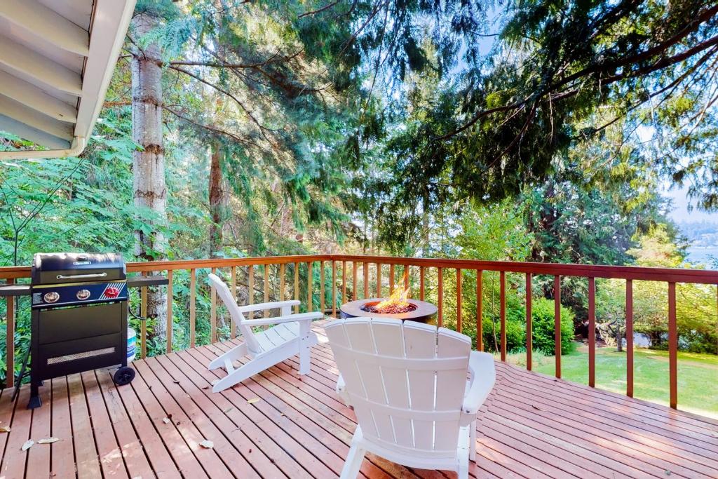 a wooden deck with a grill and chairs on it at Calamity Cabin in Gig Harbor