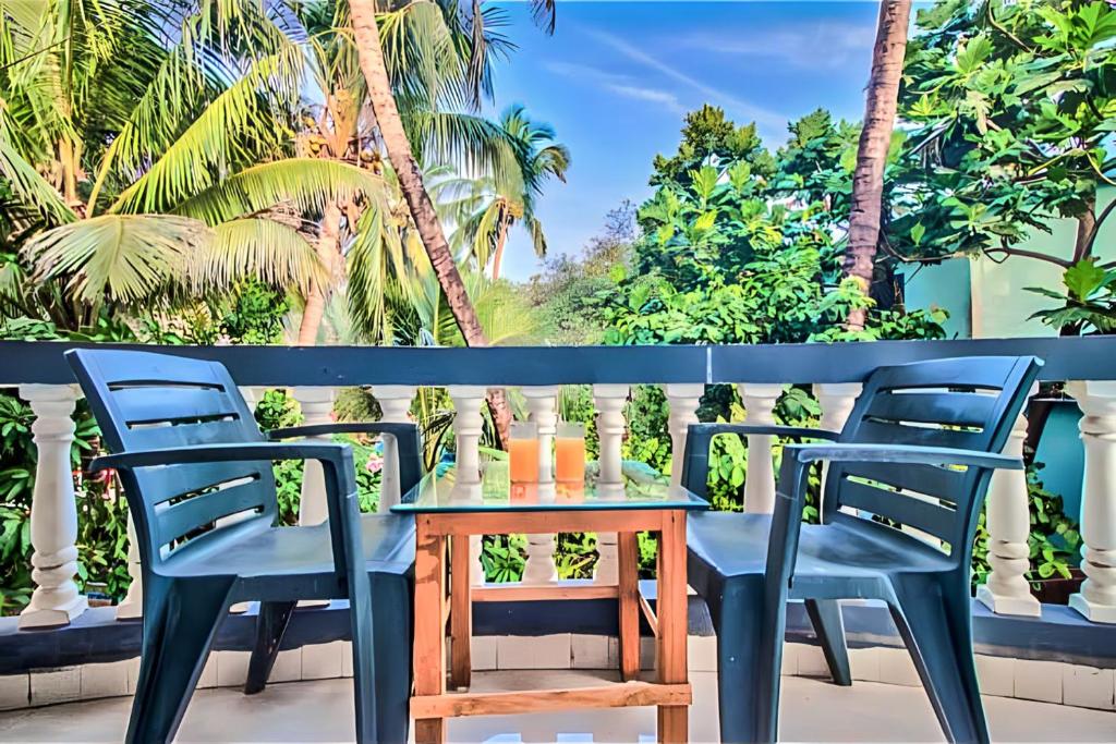 卡蘭古特的住宿－Calangute Turista，棕榈树阳台的桌椅
