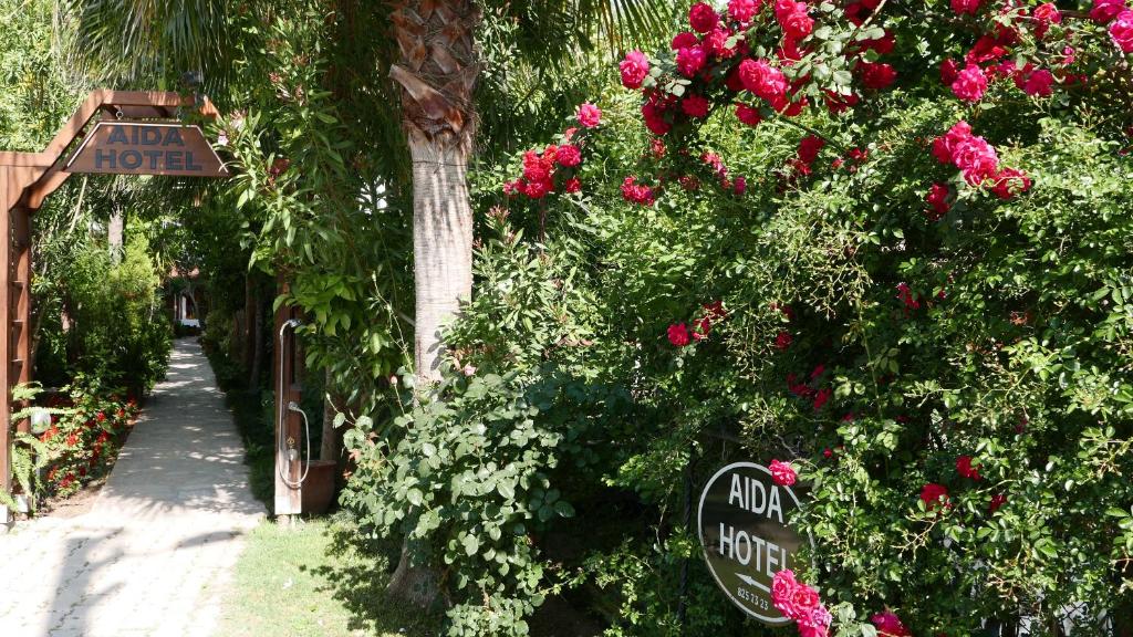 een tuin met rozen en een bord met de naam Alpha hotel bij Aida Hotel in Cıralı