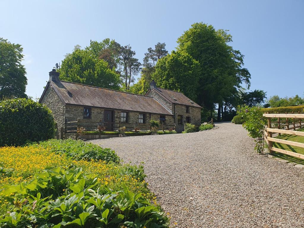 an old stone house with a fence in front of it at Ty Barcud in Lampeter