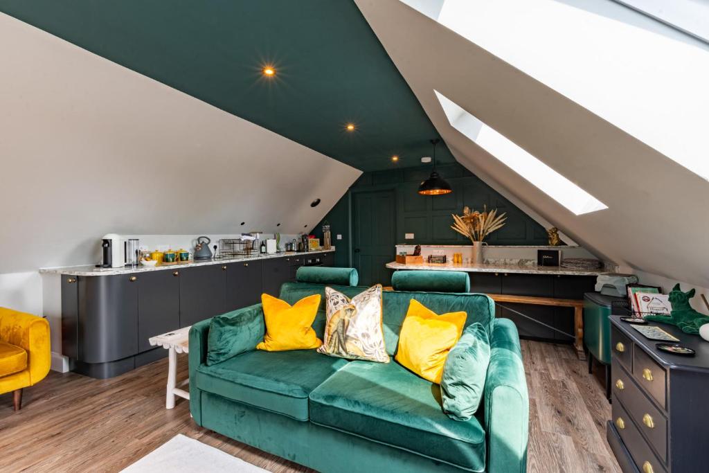 a living room with a green couch and yellow pillows at Stylish one bedroom Cotswold Coach House Tetbury in Tetbury