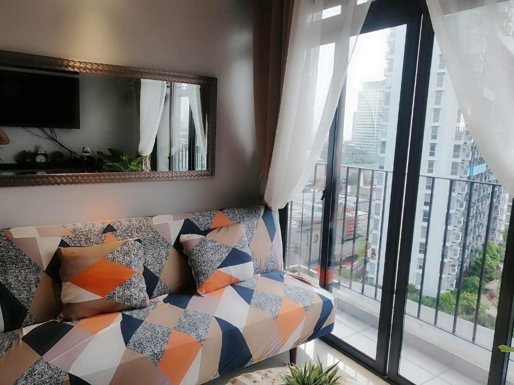 a living room with a couch and a large window at 2 BR Portovita Tower 12-A in Manila