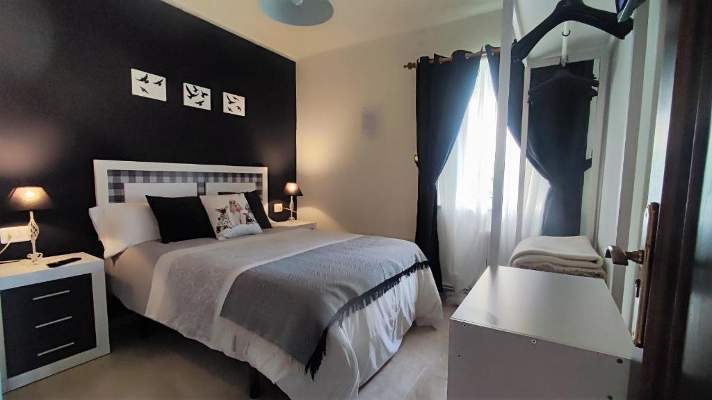 San Miguel de Reinante的住宿－Mascotas Brais，一间卧室设有一张床和黑色的墙壁