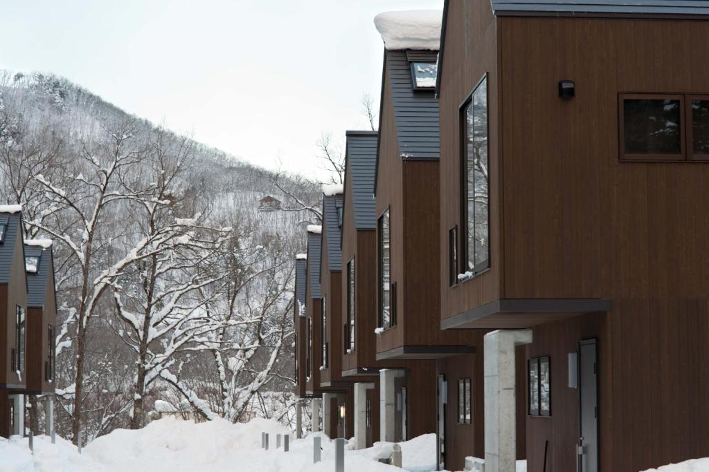 a row of buildings in the snow with trees at Gakuto Villas in Hakuba