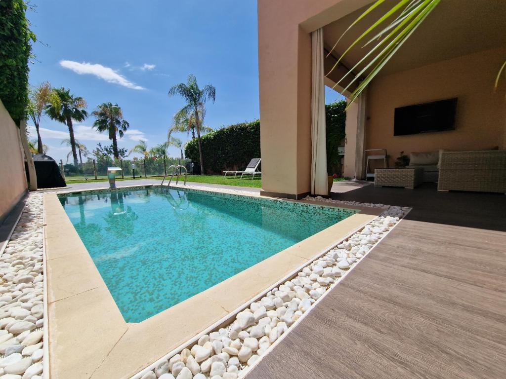 a swimming pool with rocks around a house at Villa golf prestigia marrakech in Marrakesh