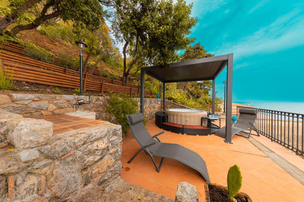 une terrasse couverte avec une table et un banc dans l'établissement Jureka Sea View Apartment 1, à Cefalù