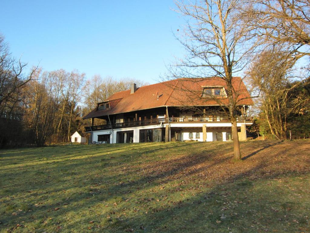 een groot huis met een rood dak op een veld bij Auszeit auf dem KulturGut Hirtscheid in Hirtscheid