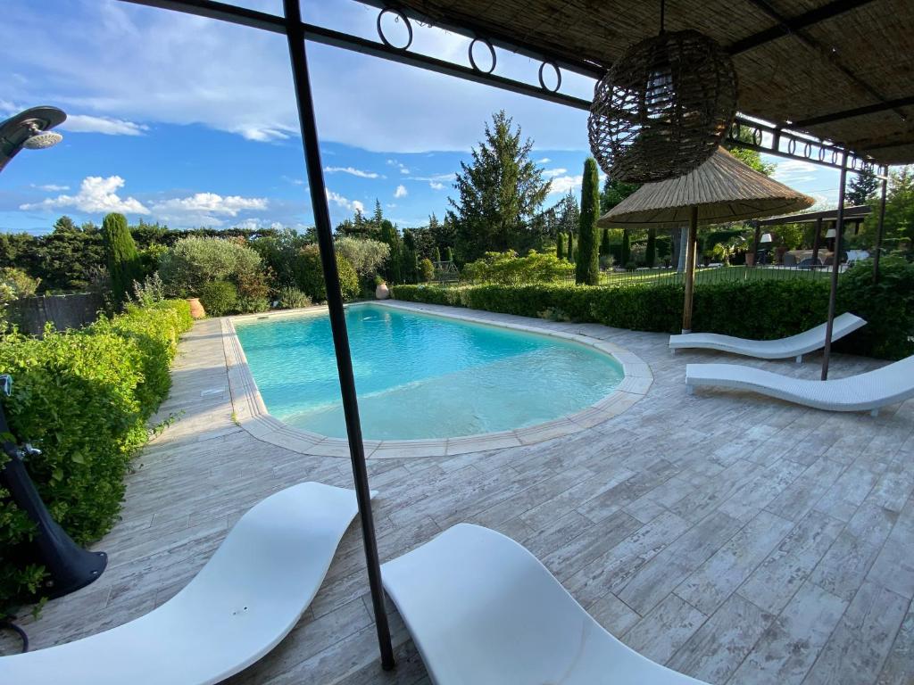 a swimming pool with white chairs and an umbrella at Villa d Agathe en Provence Graveson in Graveson