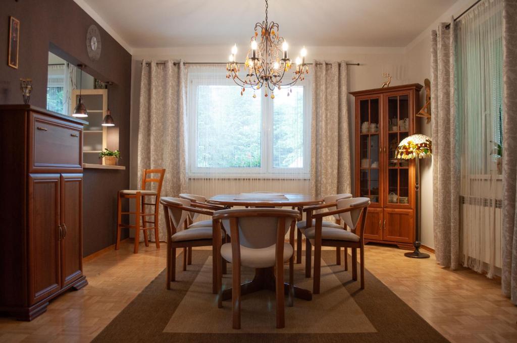 ein Esszimmer mit einem Tisch, Stühlen und einem Kronleuchter in der Unterkunft Apartament w Alejce in Rabka-Zdrój