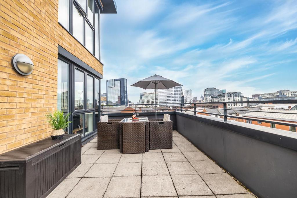 a balcony with a table and an umbrella on a building at City centre apartment with roof terrace. in Birmingham