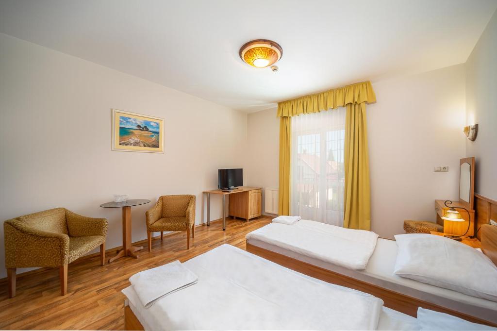 Sala de estar con 2 camas y mesa en Nefelejcs Hotel en Mezőkövesd