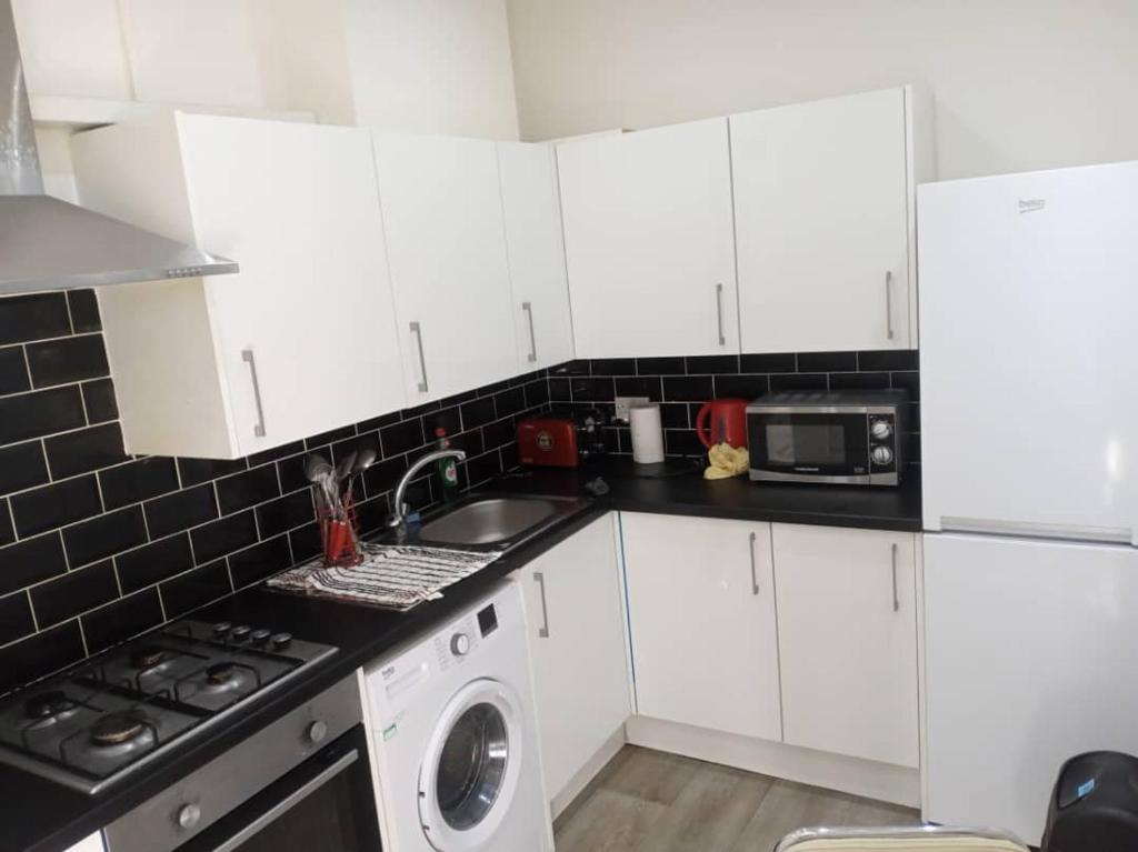 een keuken met witte kasten en een wasmachine bij Double-bed H4 close to Burnley city centre in Burnley