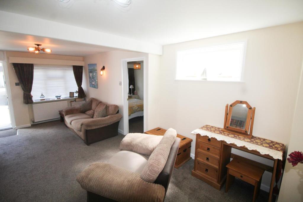 a living room with a couch and chairs and a mirror at Briar Cottage in Looe