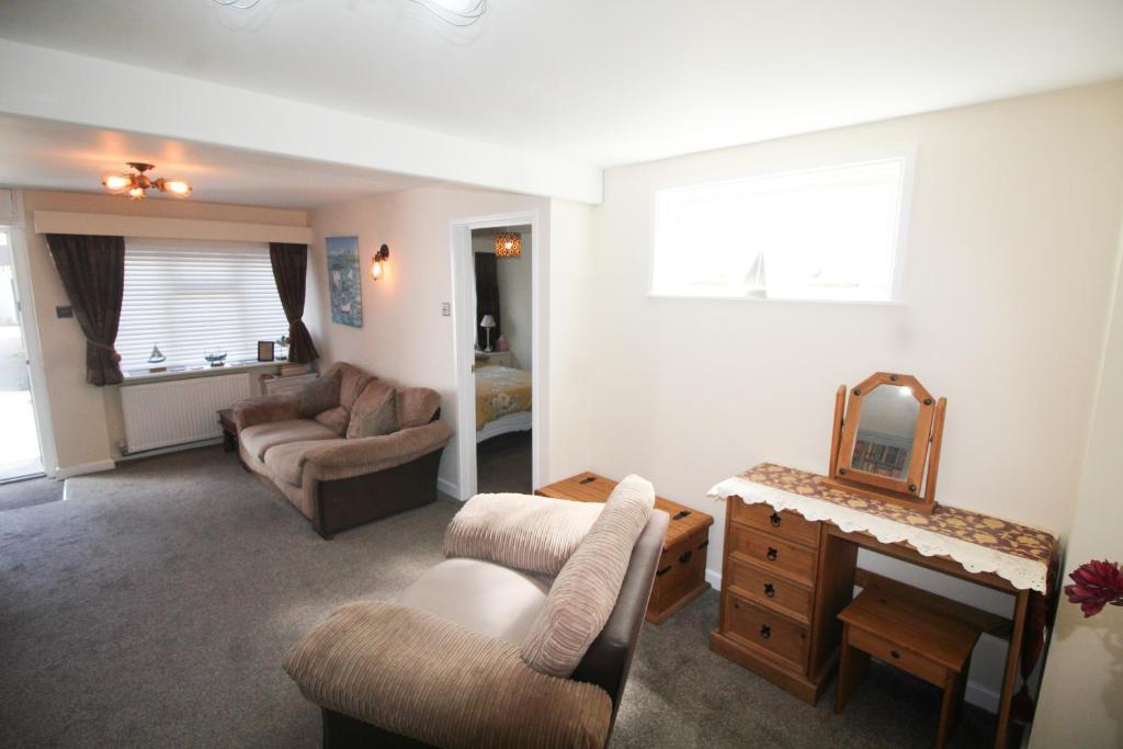un soggiorno con divano, sedie e specchio di Briar Cottage a Looe