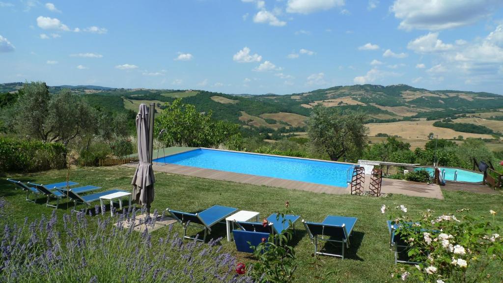 - une piscine avec des chaises et un parasol dans l'établissement Villa with private swimming pool and private garden in quiet area, panoramic views, à Radicondoli