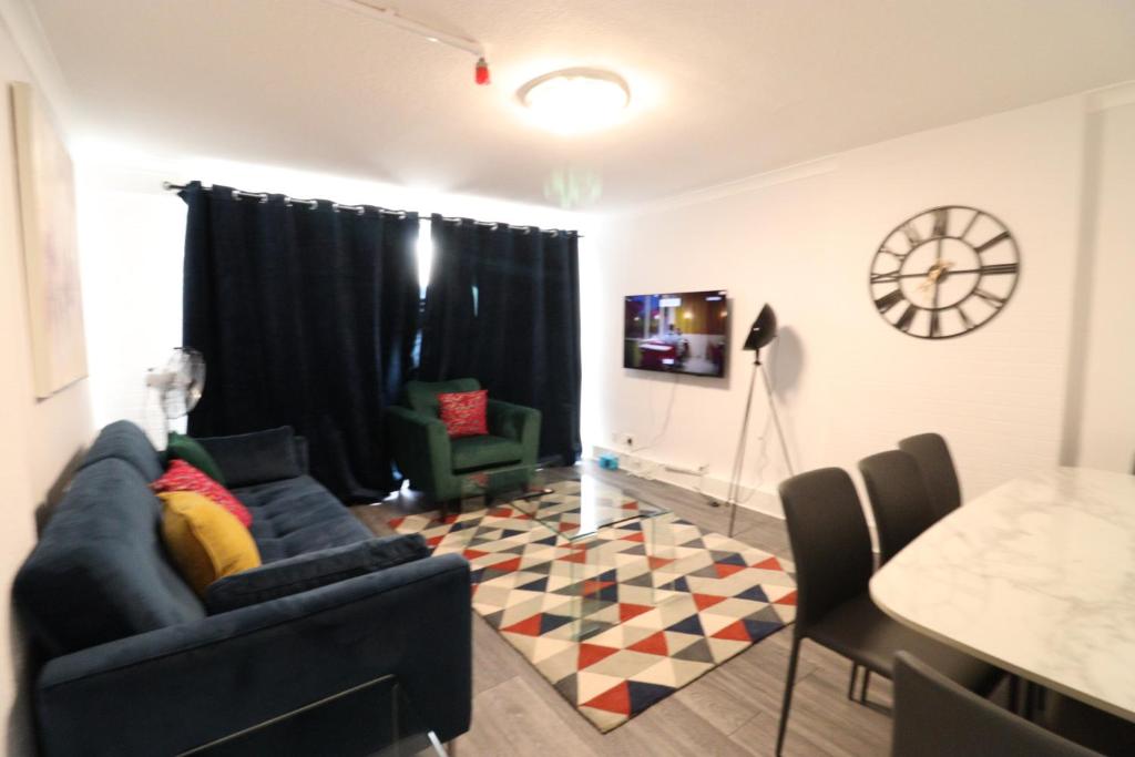 London Central Modern Apartment Charlton في لندن: غرفة معيشة مع أريكة زرقاء وطاولة