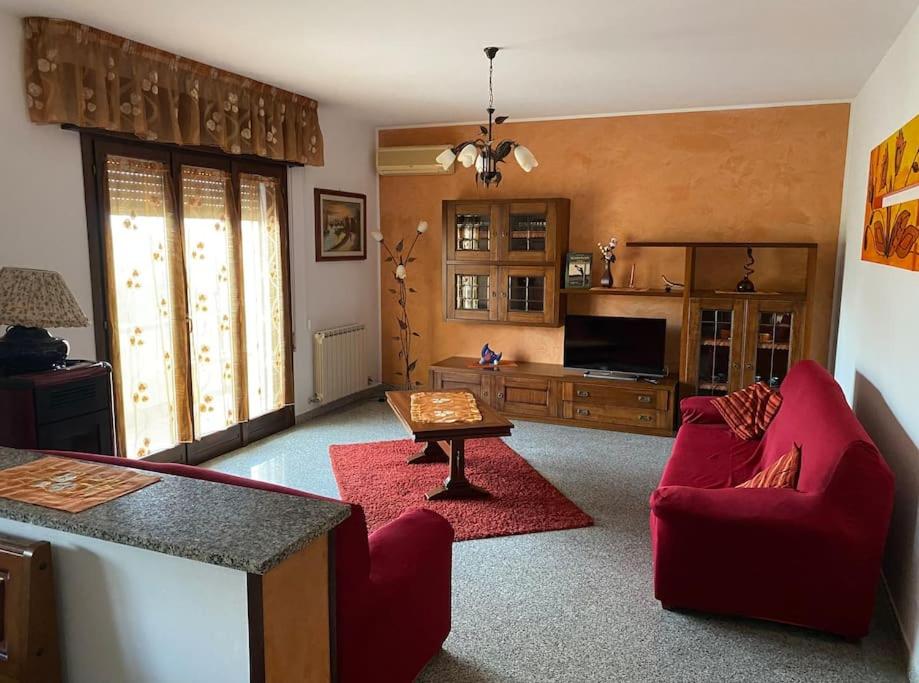 sala de estar con sofá rojo y mesa en “Casa Alex” a pochi km dal mare en Scardovari