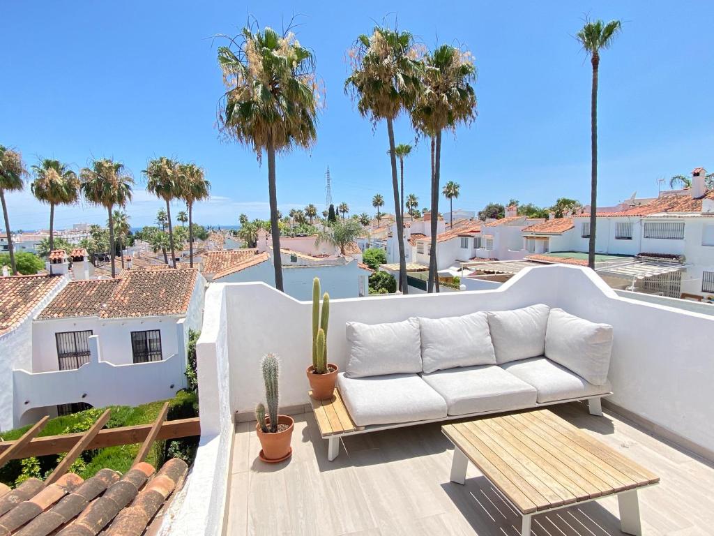 un sofá blanco en un balcón con palmeras en Townhouse w/sea view & garden, en Estepona