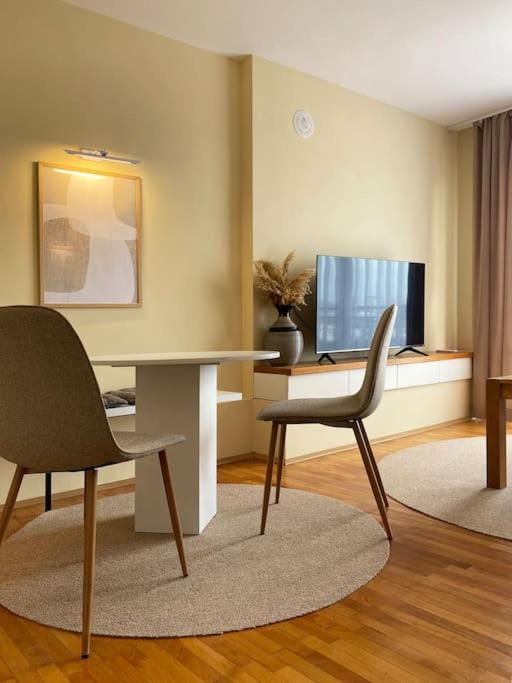 a living room with two chairs and a table and a television at Etern Stays IEG - Pristine Apartment in Prishtinë