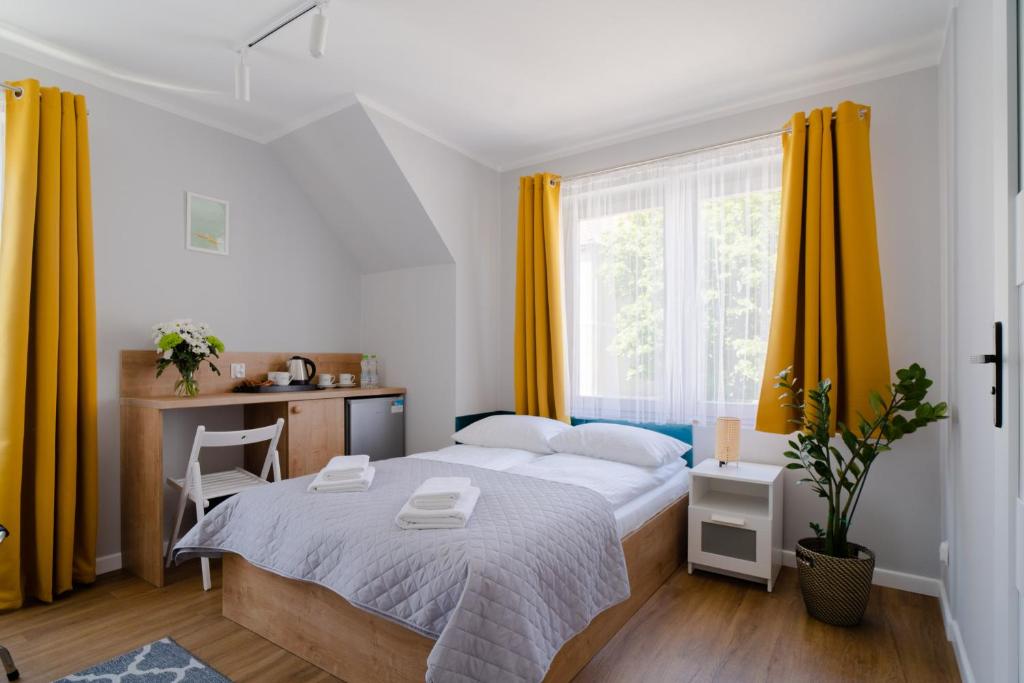 a bedroom with a bed with yellow curtains and a desk at Porta Baltica - pokoje Sopot in Sopot