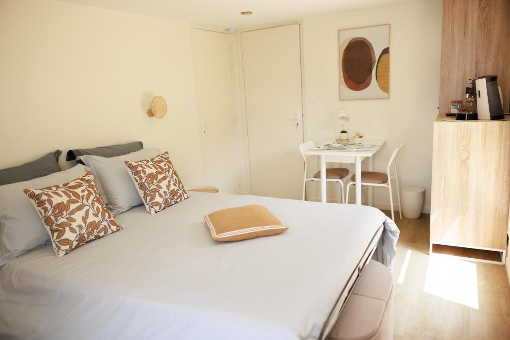 ein Schlafzimmer mit einem weißen Bett mit Kissen und einem Tisch in der Unterkunft Pierre de Lune in Bayeux