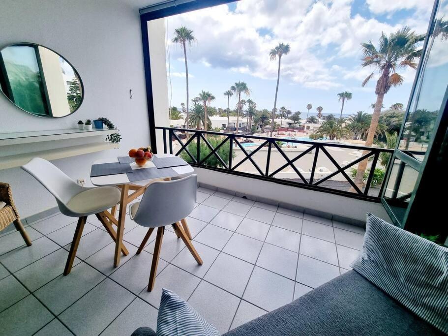 una camera con tavolo e sedie e un balcone con palme di Luxury Ocean View Playa Roca a Costa Teguise