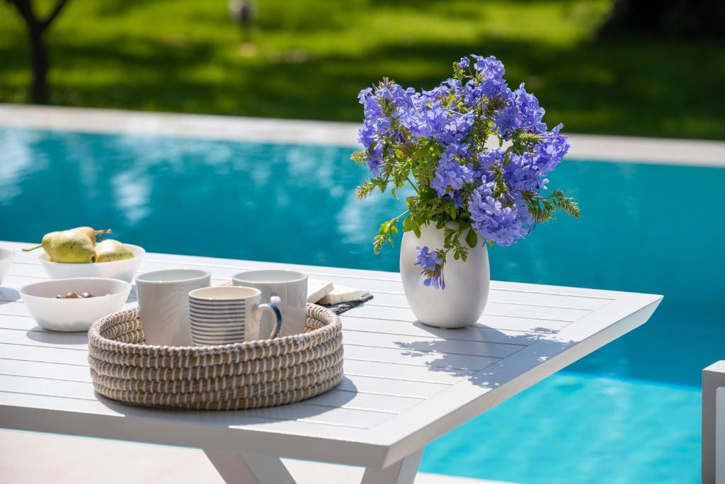 a table with cups and a vase of purple flowers at Averto Villas with private pool in Nydri
