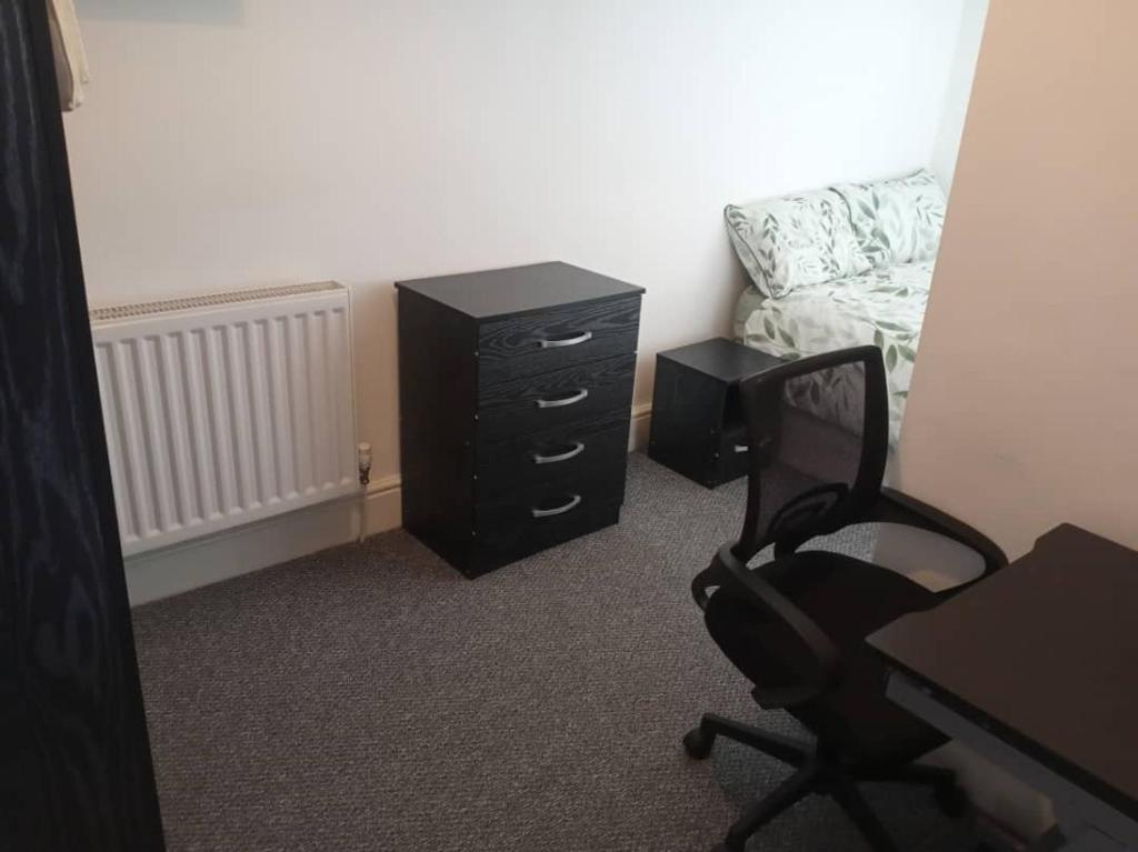 ein Schlafzimmer mit einem Schreibtisch, einem Stuhl und einer Kommode in der Unterkunft Double bed (R2) close to Burnley city centre in Burnley