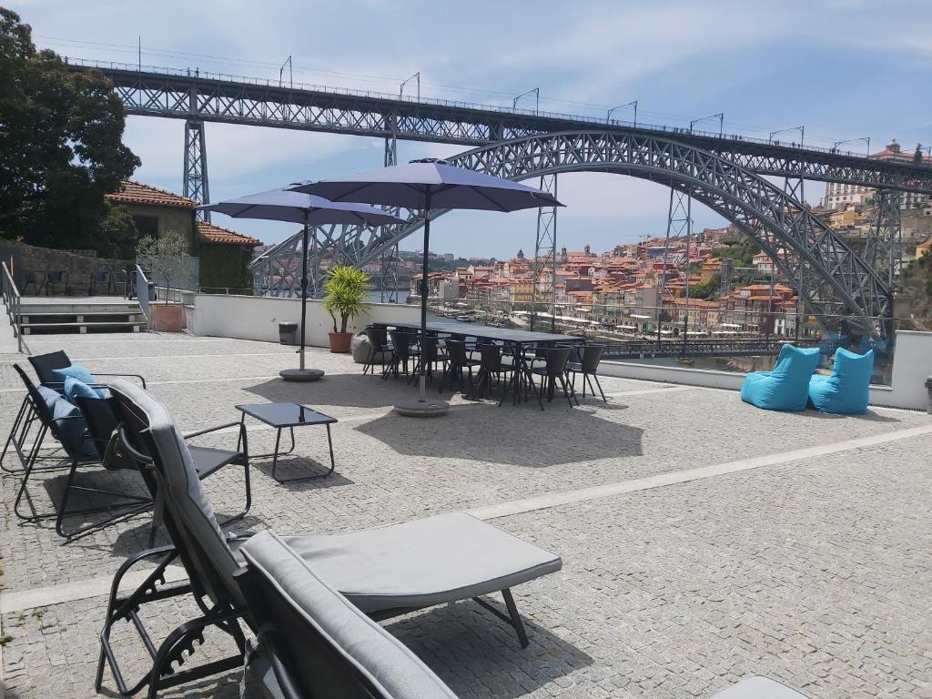 un patio avec des tables et des parasols en face d'un pont dans l'établissement Bridge It - Suites & Views, à Vila Nova de Gaia