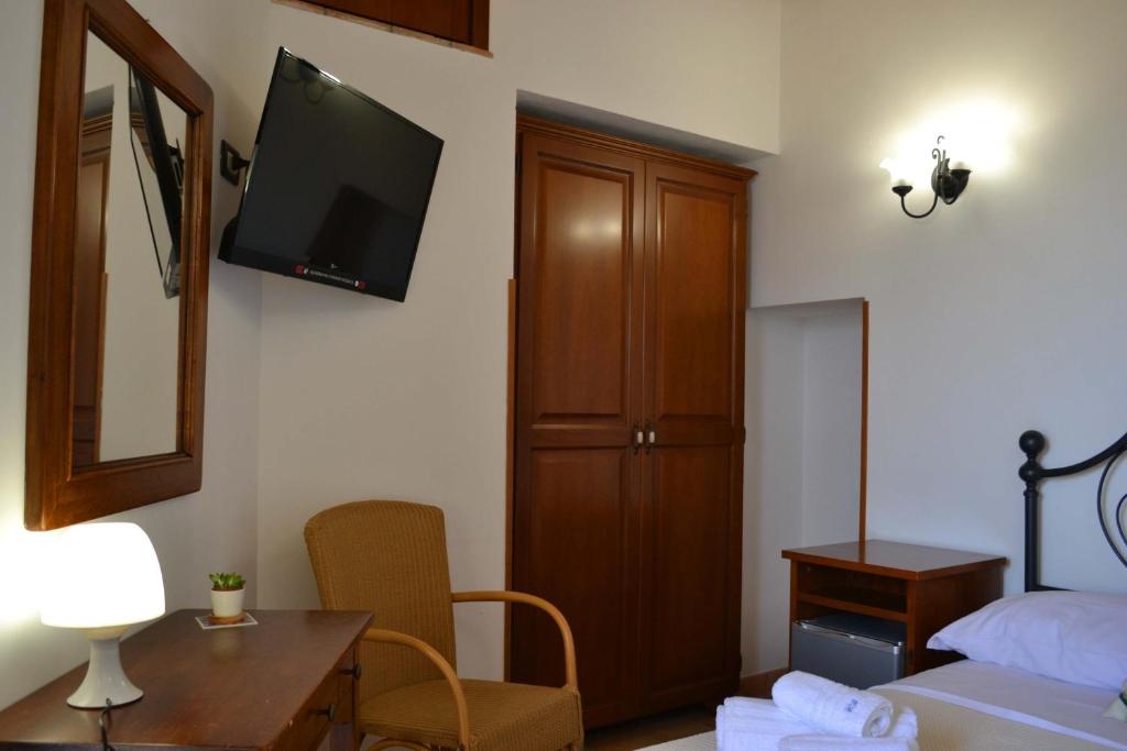 1 dormitorio con 1 cama y TV en la pared en HOTEL Cala Buguto, en Custonaci