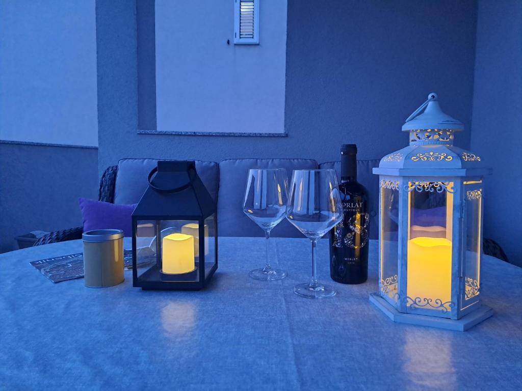 un tavolo con due bicchieri, una lanterna e bottiglie di vino di Apartment Mira a Šibenik
