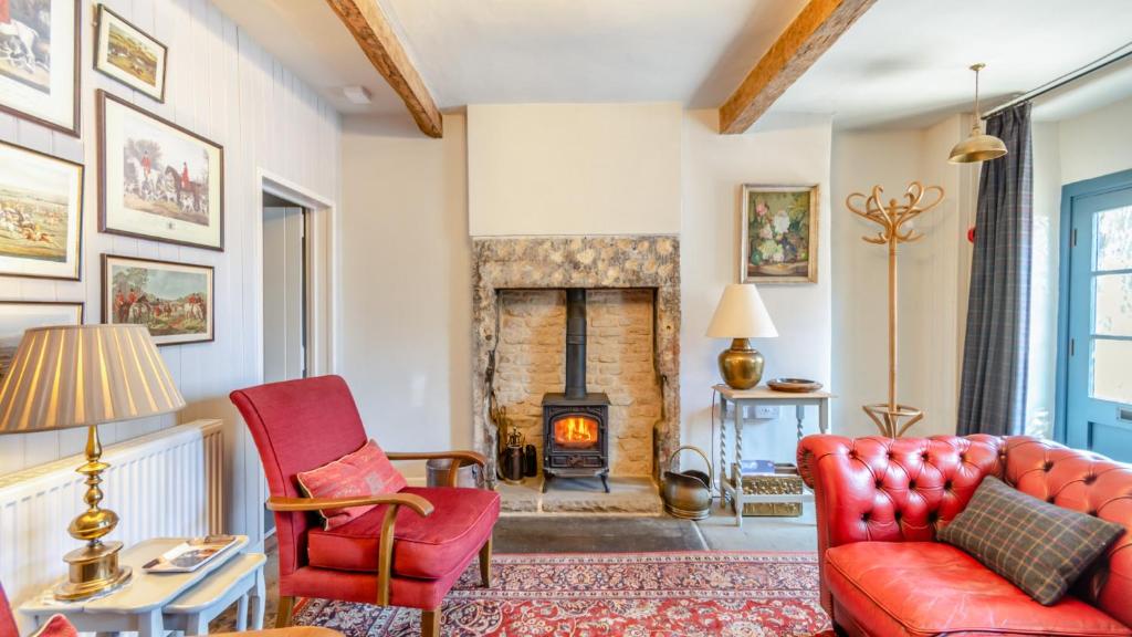 a living room with red chairs and a fireplace at Rose Cottage in Youlgreave