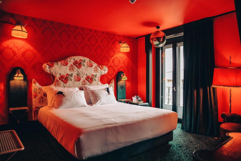 Pensão Amor Madam's Lodge في لشبونة: غرفة نوم بجدران حمراء وسرير كبير