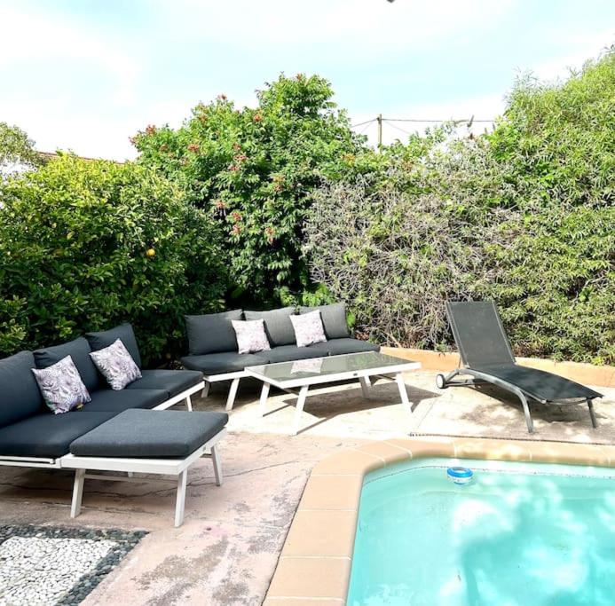 una piscina con sofás y sillas junto a en Espace Les Orangers - Piscine - 10mn plages, en Six-Fours-les-Plages
