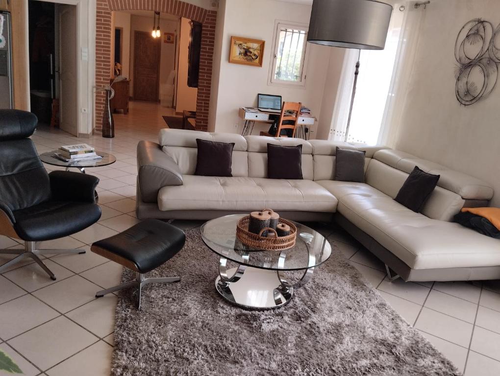uma sala de estar com um sofá, uma mesa e cadeiras em Villa spacieuse em Aussonne
