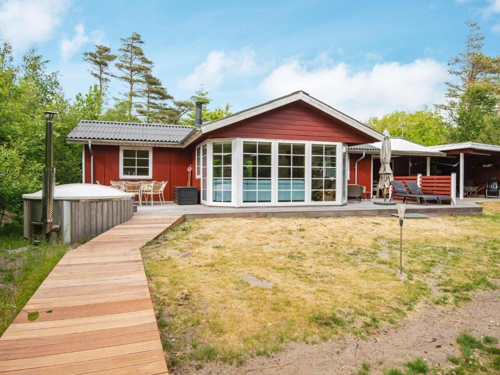 a red house with a wooden deck in front of it at 6 person holiday home in Hemmet in Hemmet
