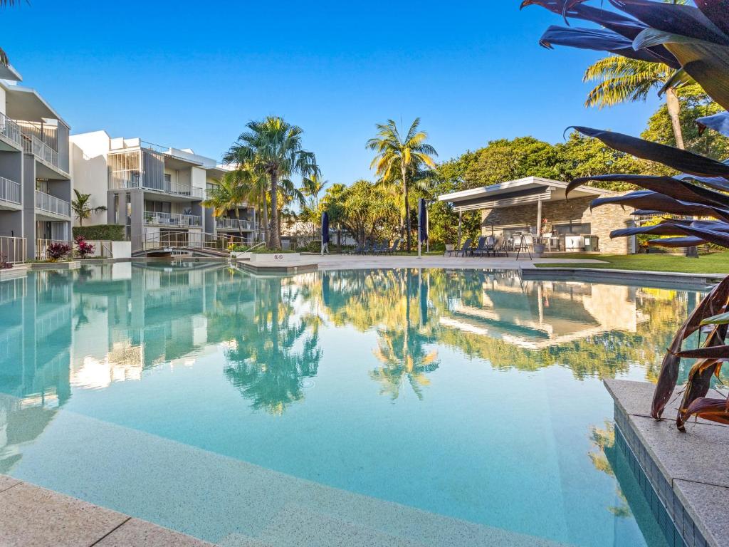 a swimming pool with palm trees in a resort at Drift North Beachfront Apartments - Private Apartments in Kingscliff