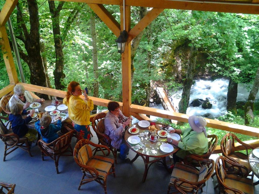 eine Gruppe von Menschen, die an einem Tisch auf einem Deck sitzen in der Unterkunft Hotel Ravnjak in Dobrilovina