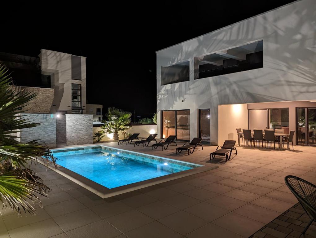 a swimming pool in front of a house at night at Villa SunSet in Privlaka