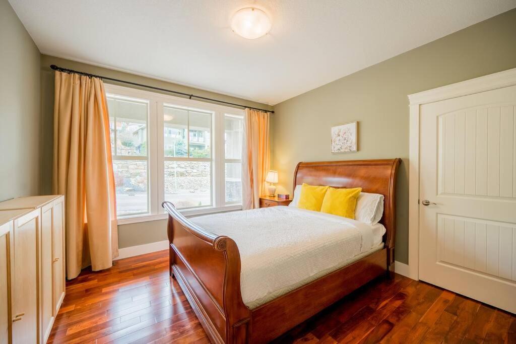 a bedroom with a bed with yellow pillows and a window at Kelowna Spacious 2 Bedrooms House in Kelowna