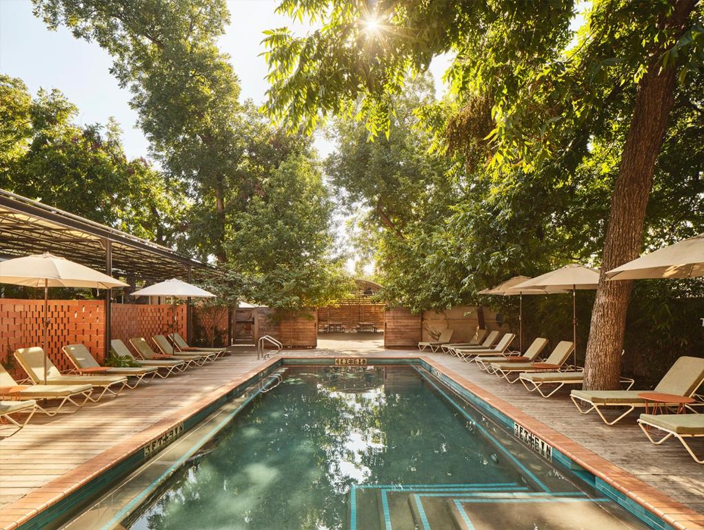 a swimming pool with chairs and umbrellas at The Carpenter Hotel in Austin