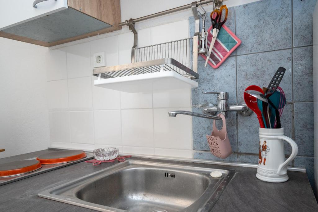 zlew kuchenny z przyborami kuchennymi w kubku w obiekcie Apartment Preko 8179b w mieście Preko