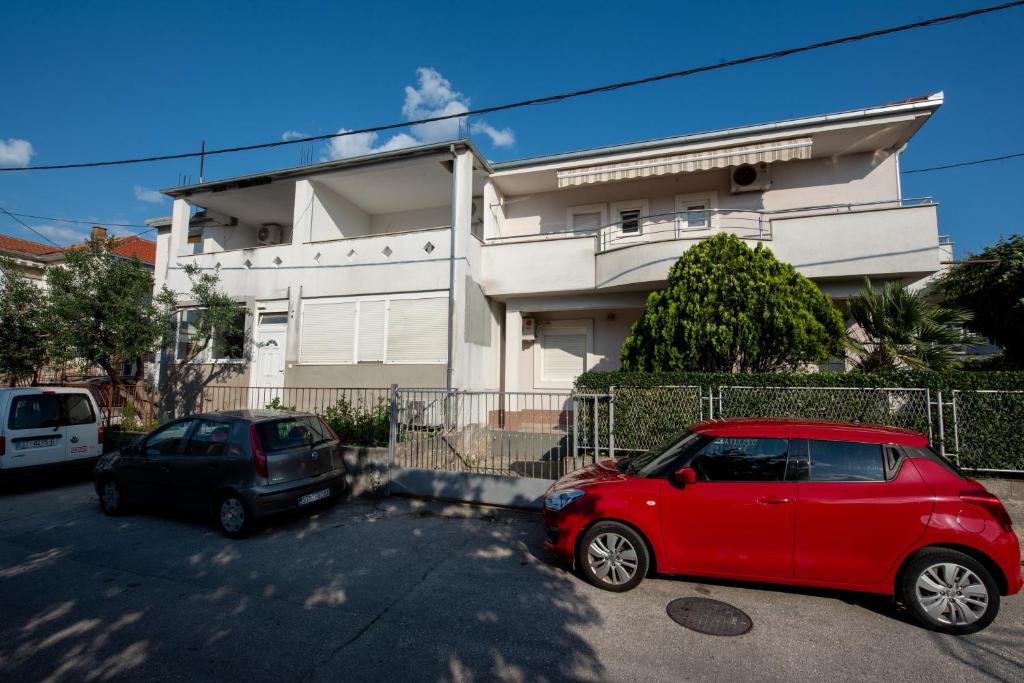 une voiture rouge et une voiture noire garées devant un bâtiment dans l'établissement Apartments with a parking space Split - 21525, à Split