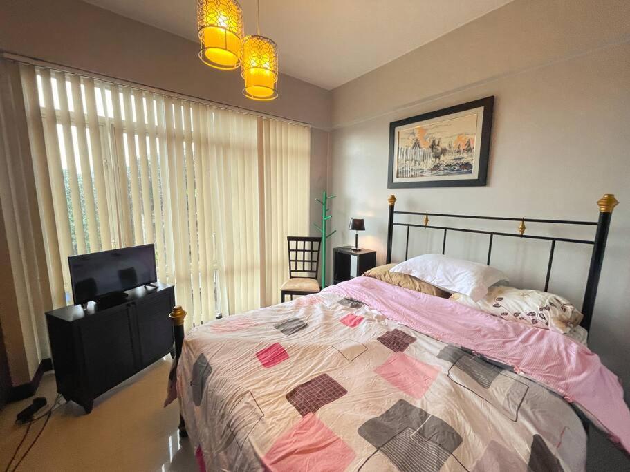 a bedroom with a bed and a flat screen tv at Lovely & Stylish 1BR in Mckinley Hill with View in Manila