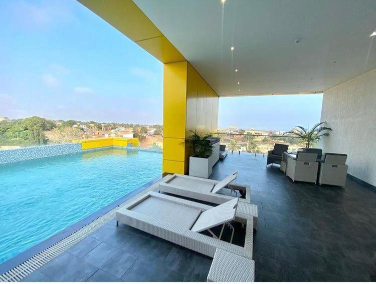 a room with a pool with chairs and a swimming pool at THE EDGE in Accra
